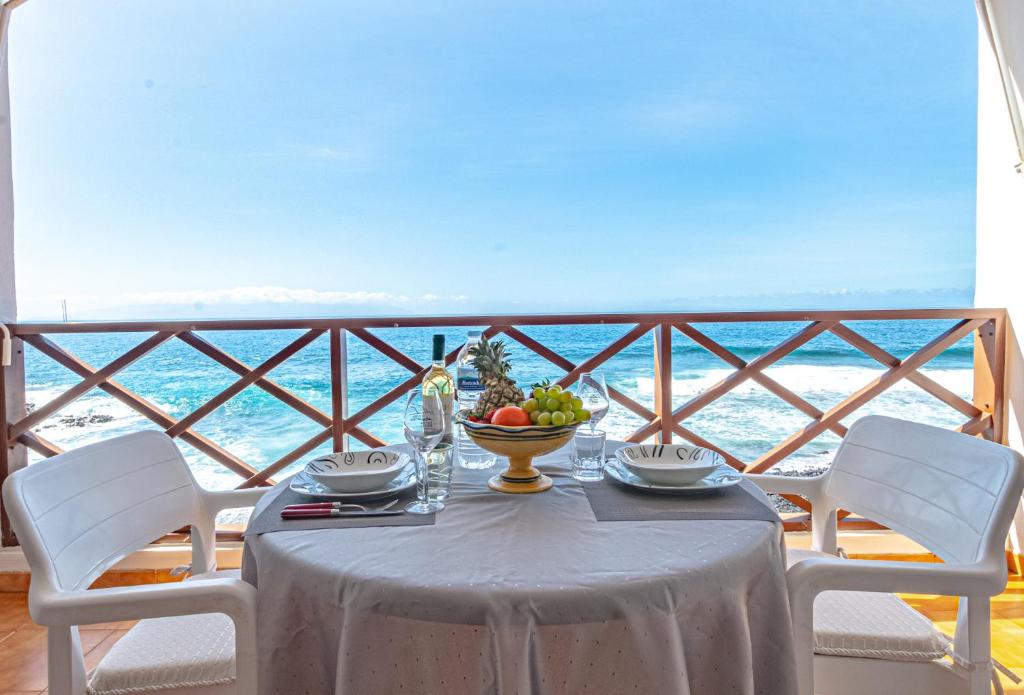 einen Tisch mit einer Obstschale auf dem Balkon in der Unterkunft Oceanfront Neptuno Apartment by Dream Homes Tenerife in Puerto de Santiago
