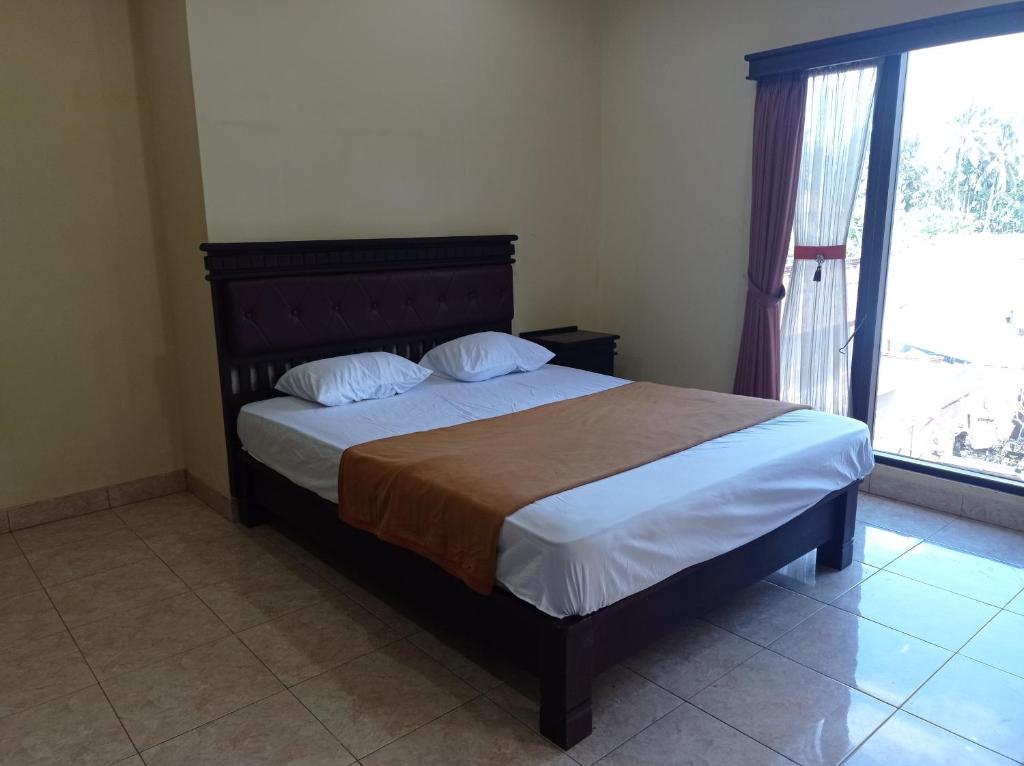 a bedroom with a bed and a large window at Hotel Mawar Sari Mitra RedDoorz in Payangan