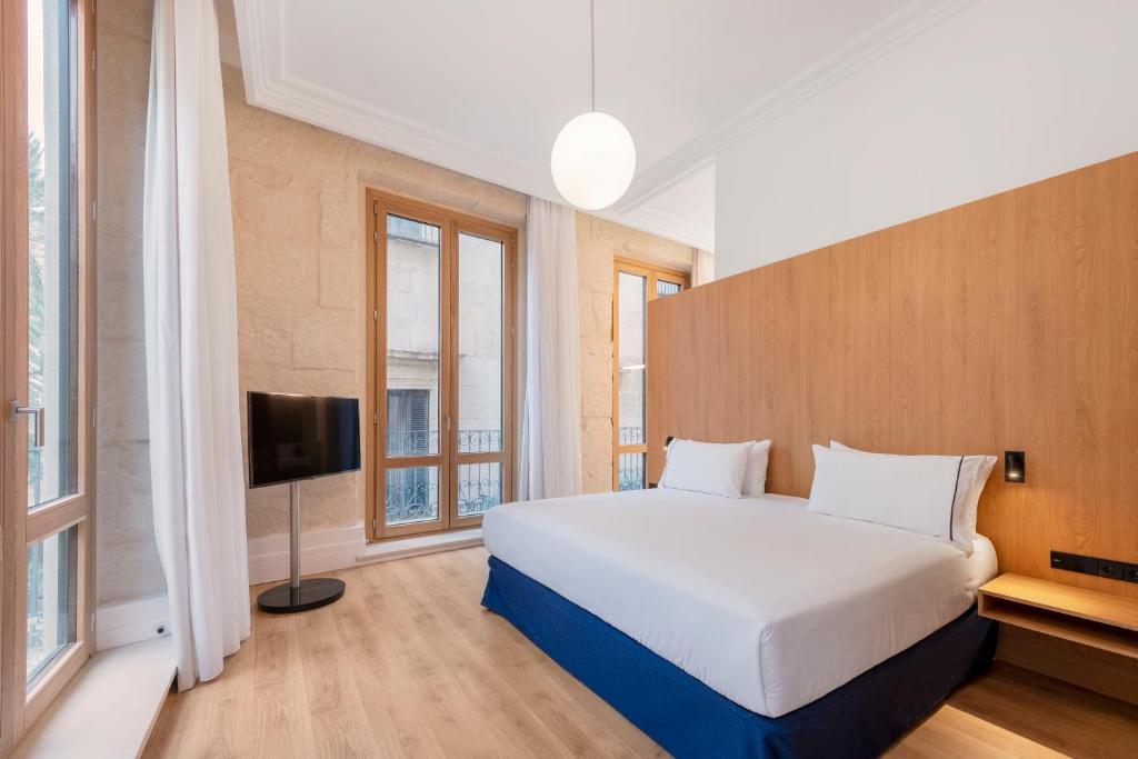 - une chambre avec un grand lit blanc et des fenêtres dans l'établissement Eurostars Pórtico Alicante, à Alicante
