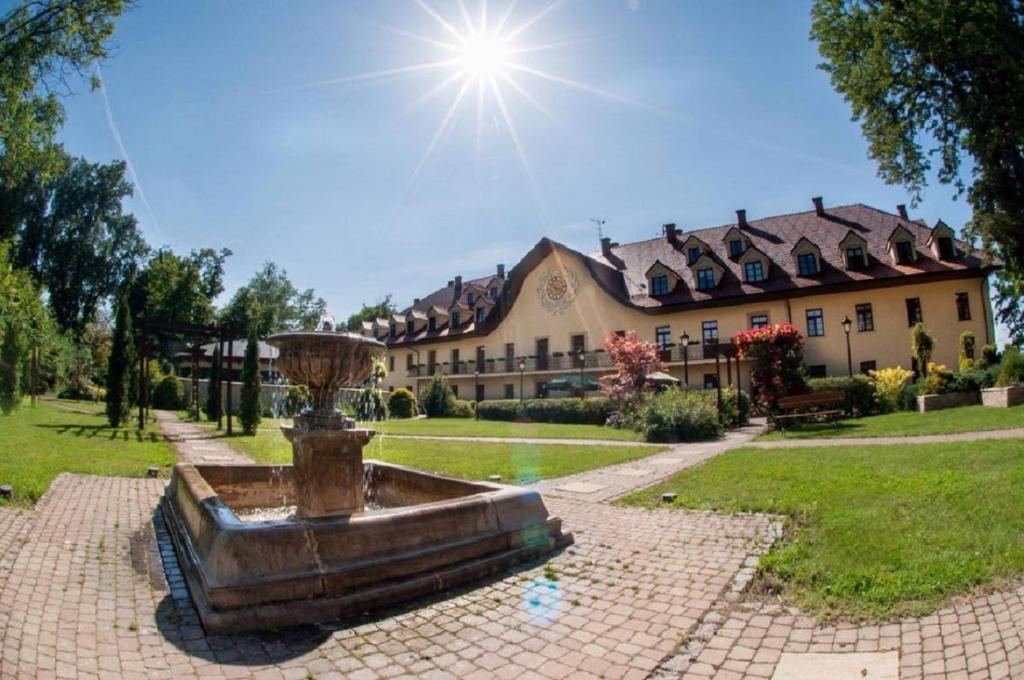 sunlit hotel courtyard featuring central stone fountain and manicured lawns under a bright sky