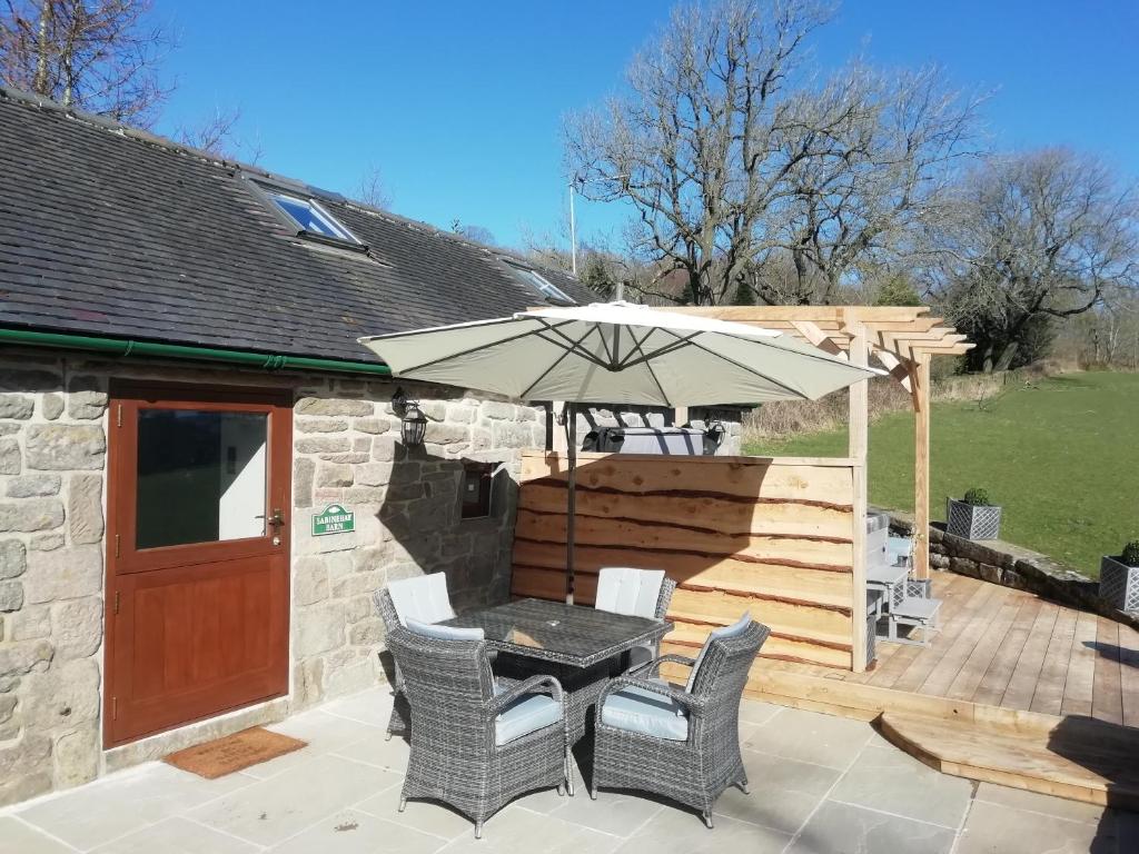 a patio with an umbrella and a table and chairs at Sabine Hay Barn in Matlock