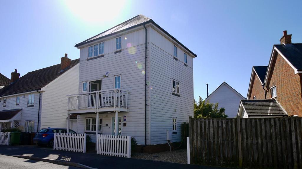 a white house with a fence in front of it at The Salty Dog holiday cottage, Camber Sands in Rye