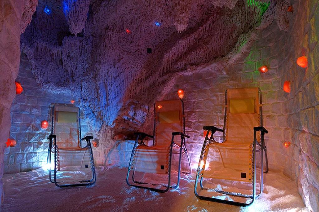 Salt cave relaxation room with reclining chairs, ambient colored lighting and salt-covered floor