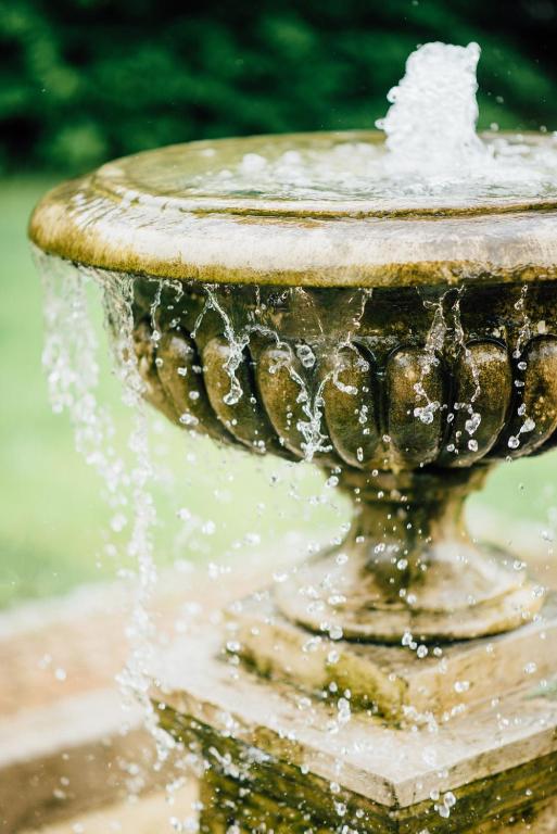 close-up stone fountain with water spilling over scalloped basin, droplets frozen midair