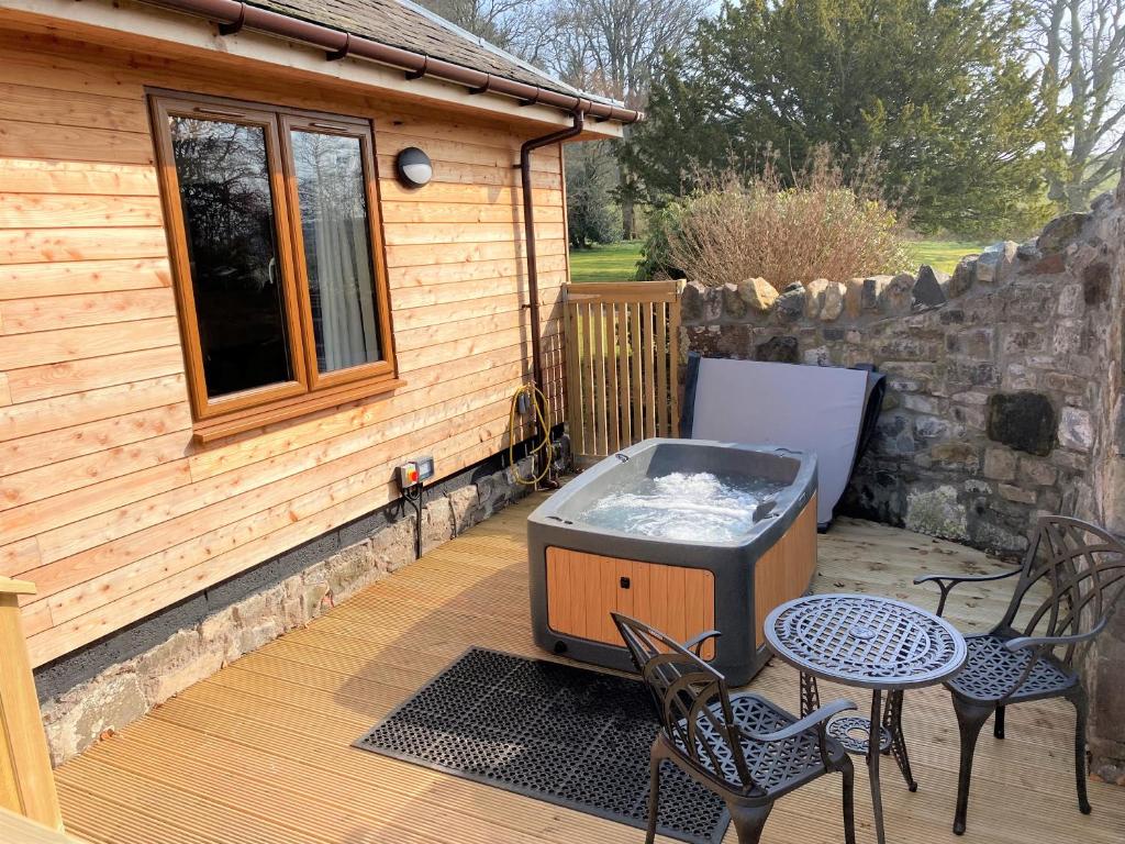 Forgandenny的住宿－Pheasant Lodge with Hot Tub，甲板上的烧烤架,配有椅子和桌子