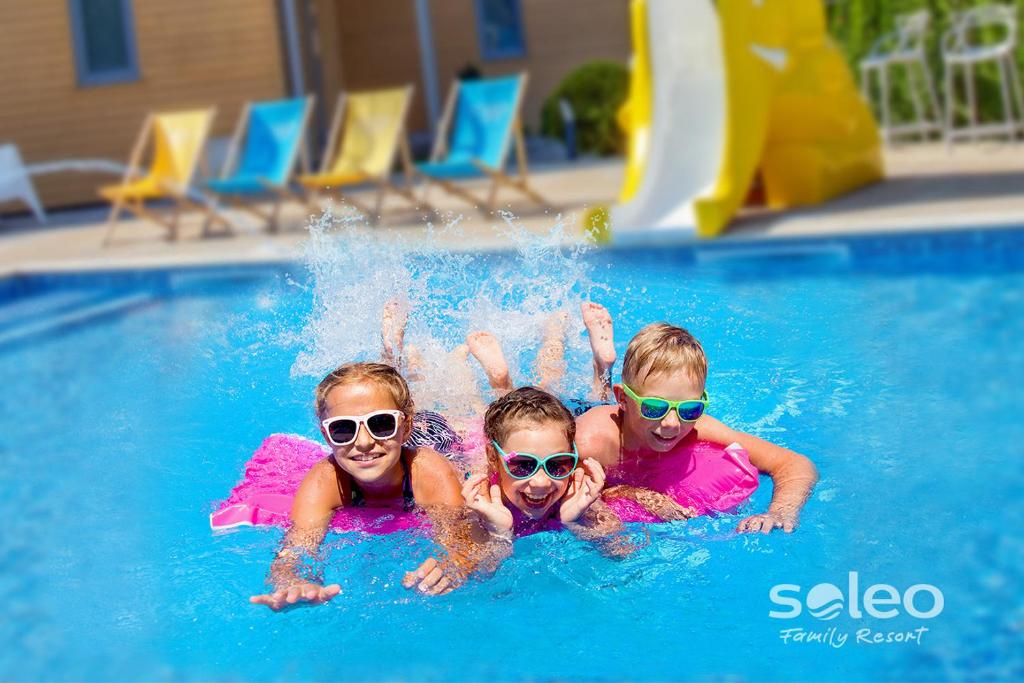 3 bambini in una piscina con occhiali da sole di SOLEO Family Resort a Rewal