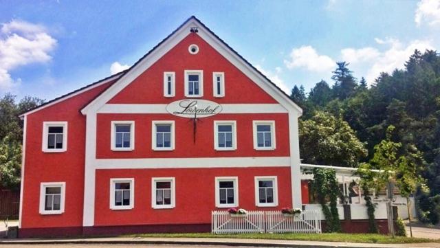 - un grand bâtiment rouge et blanc avec un panneau dans l'établissement Löwenhof, à Krumbach