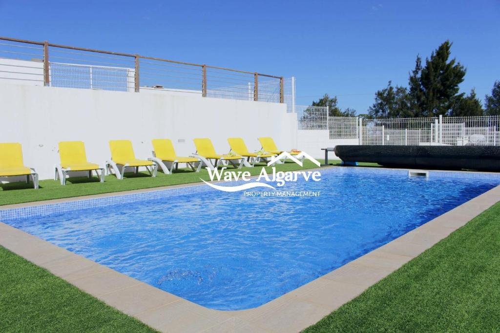 a swimming pool with chairs in the grass at Villa Salinas in Castro Marim By Wave Algarve in Castro Marim