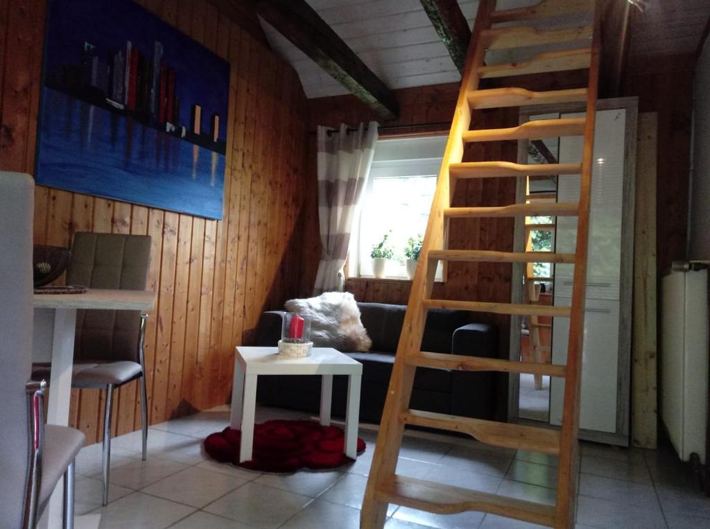 a wooden staircase in a room with a table at 25qm großes Ferienhäuschen " Der Hengstall" auf unserem Reiterhof in Birkenbeul