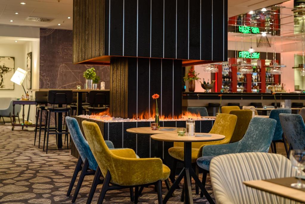 um restaurante com mesas e cadeiras e um bar em Mercure Hotel Bochum City em Bochum