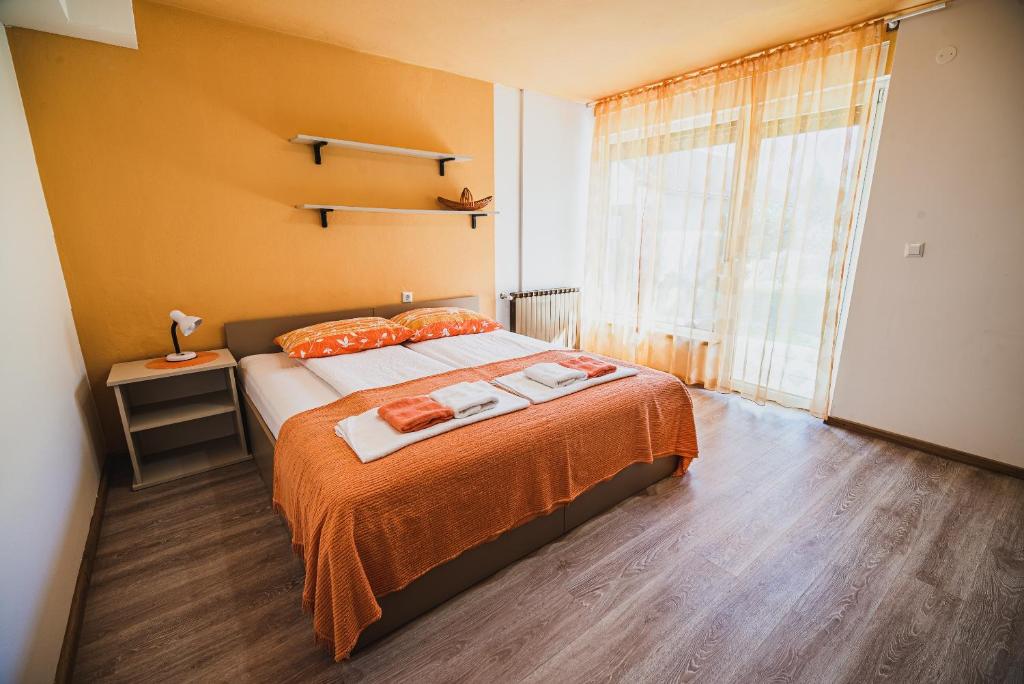 a bedroom with a bed with orange sheets and a window at Apartma Rombon Brdo with Free Onsite Parking in Bovec
