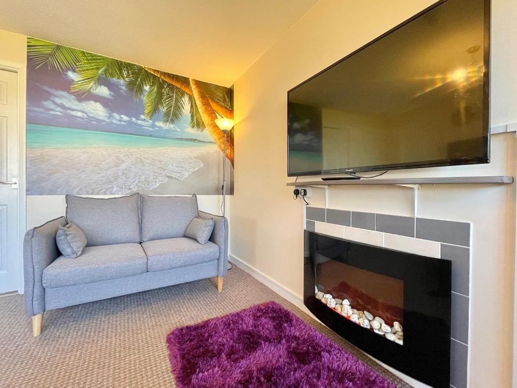 a living room with a tv and a couch and a fireplace at Paradaise Immaculate 2-bed property Hemsby in Hemsby