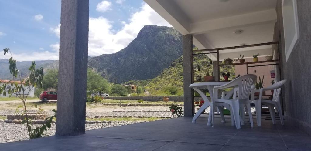 un porche con 2 sillas, una mesa y una montaña en Cabañas Cafayate I en Cafayate