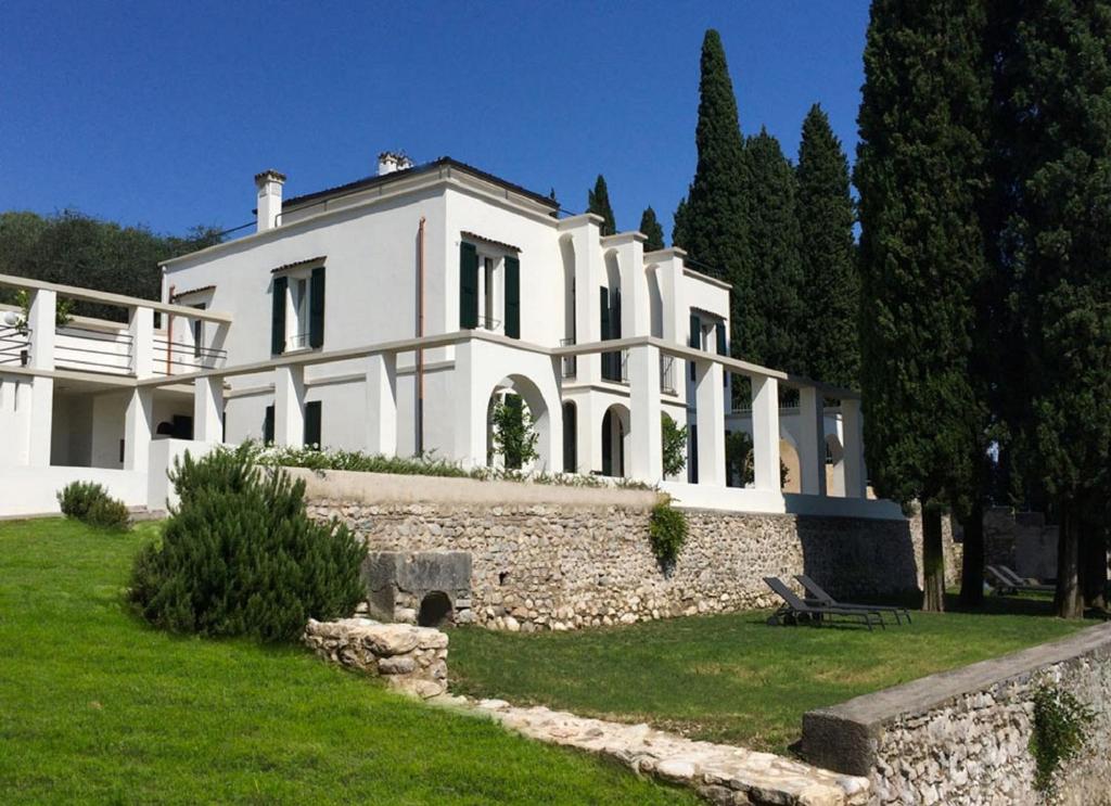 a large white house with a stone wall at Washington Apartments al Vittoriale in Gardone Riviera