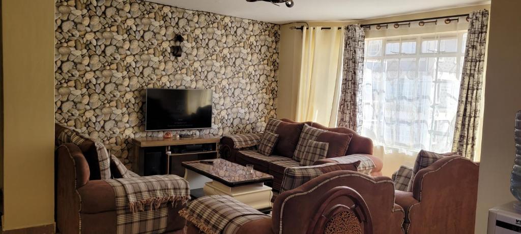 uma sala de estar com sofás e uma televisão em Ree homestay and safaris -JKIA em Nairobi