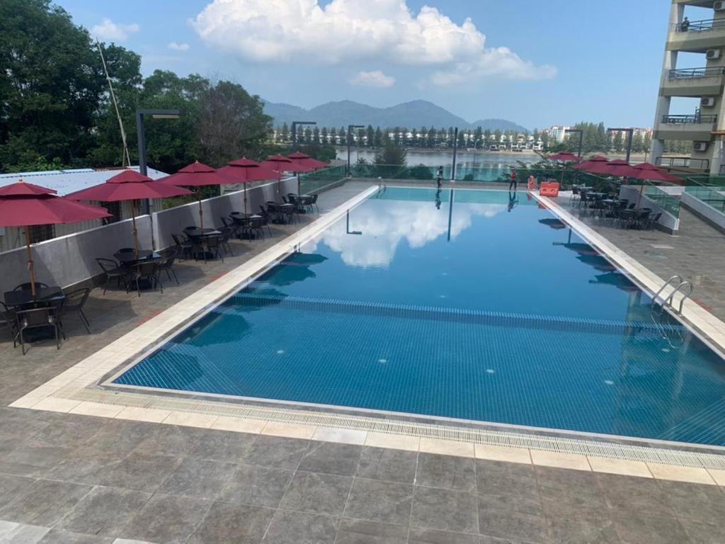 ein großer Pool mit Tischen und roten Sonnenschirmen in der Unterkunft Marina heights hotel residence in Lumut