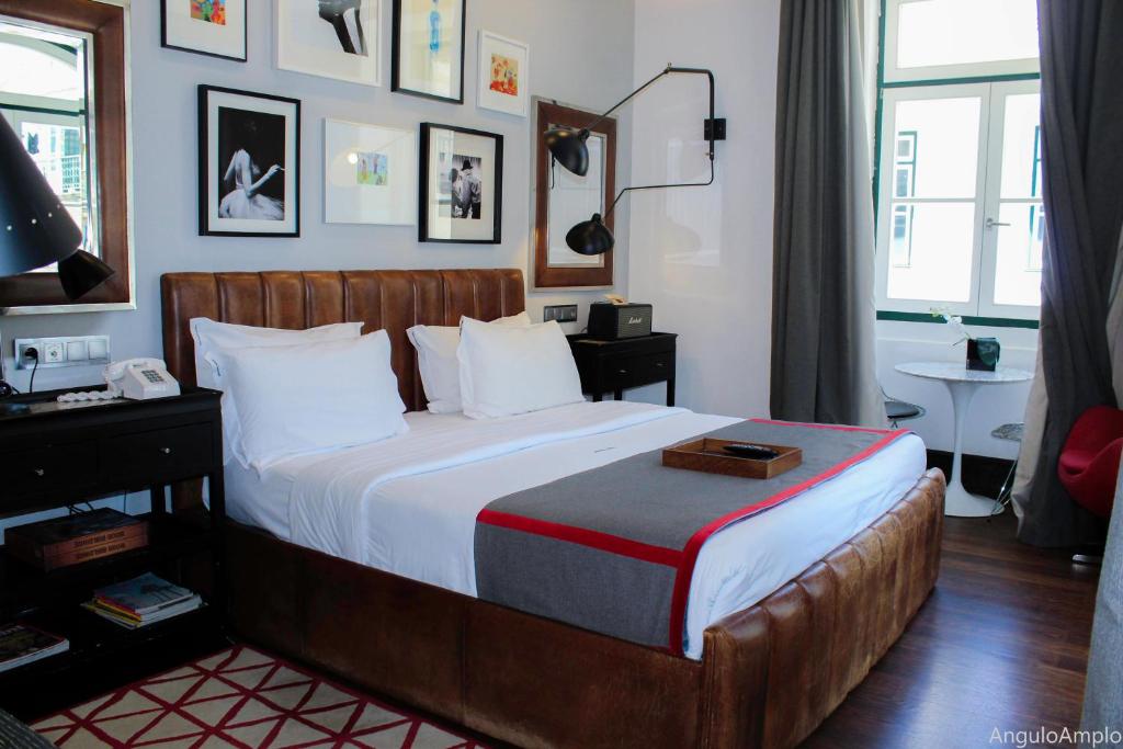 A leather-framed bedroom with a red-edged runner, artwork and a window-side seating nook.