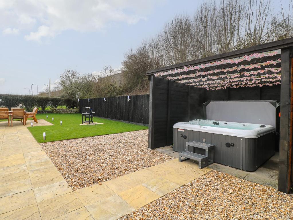 un patio trasero con bañera de hidromasaje y pabellón en Bankside House, en Melton Mowbray