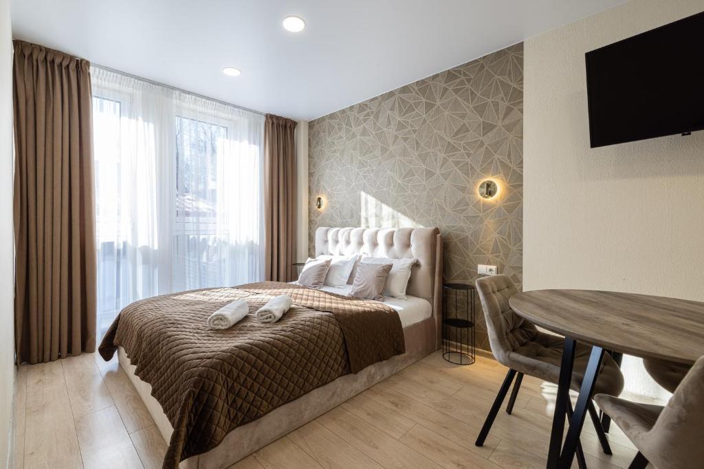 a bedroom with a bed with a table and a television at HARMONY Stay APARTAMENTAI in Telšiai