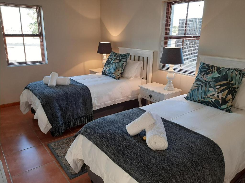 a bedroom with two beds and two windows at Nieuwedrift accommodation in Piketberg