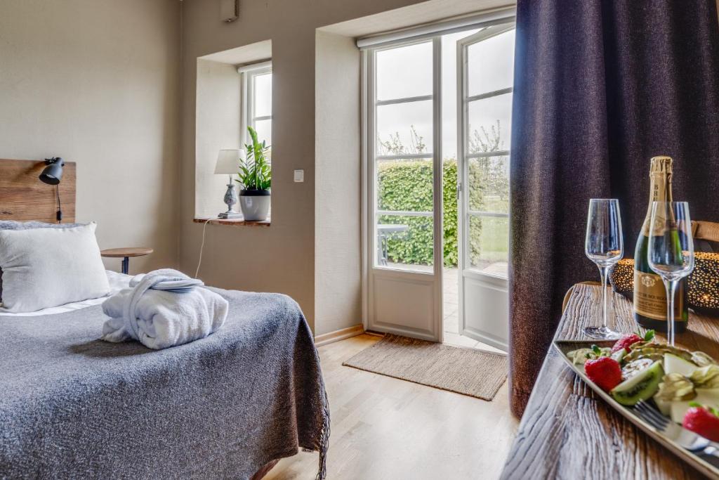 Habitación de hotel con cama y mesa con copas de vino en Örums Nygård Gårdshotell, en Löderup