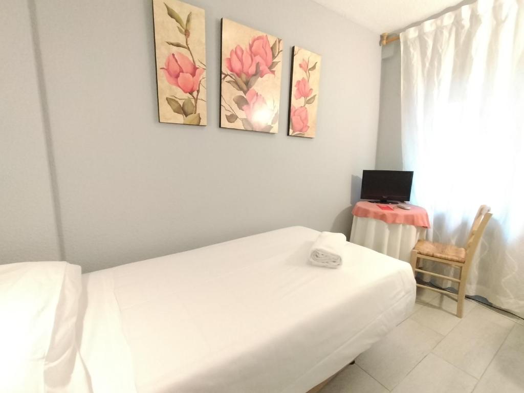 1 dormitorio con 1 cama blanca y 3 pinturas en la pared en Hostal Albero by gaiarooms, en Salamanca