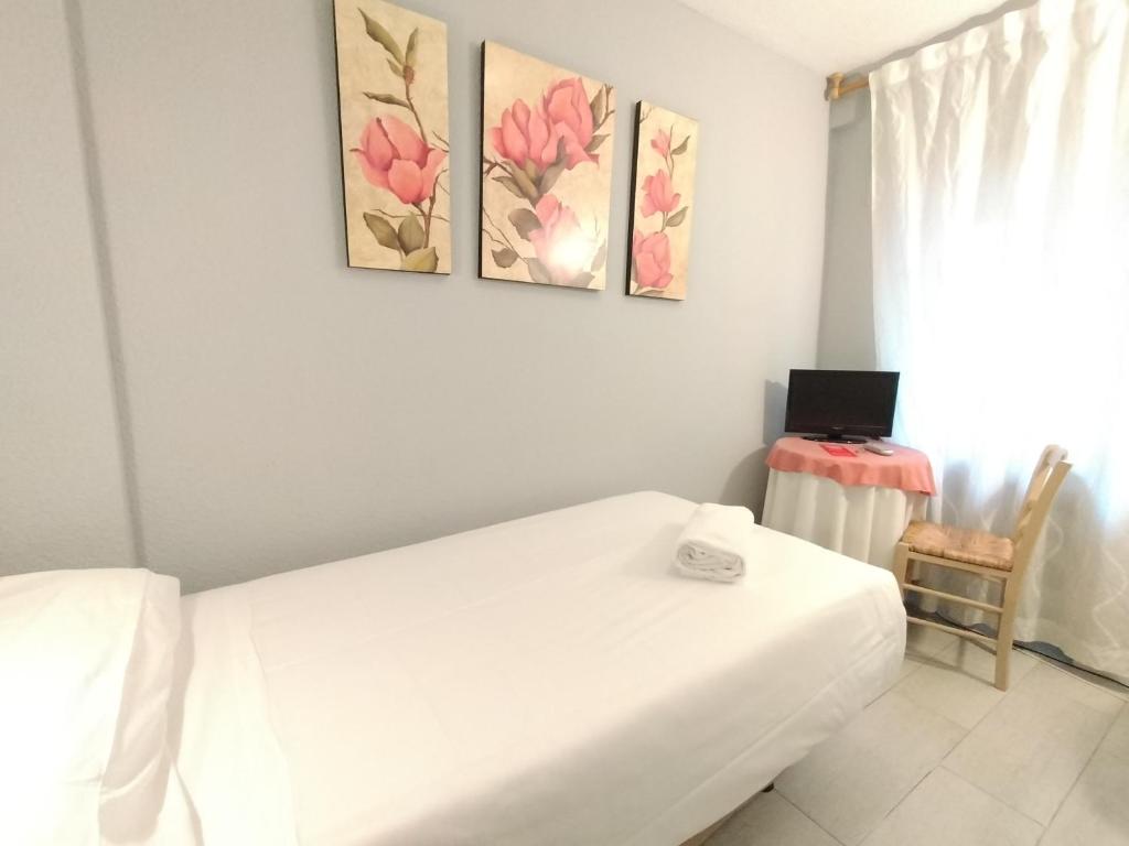 1 dormitorio con 1 cama blanca y 2 cuadros en la pared en Hostal Albero by gaiarooms, en Salamanca