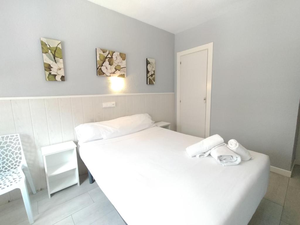 a white bedroom with a bed and a chair at Hostal Albero by gaiarooms in Salamanca