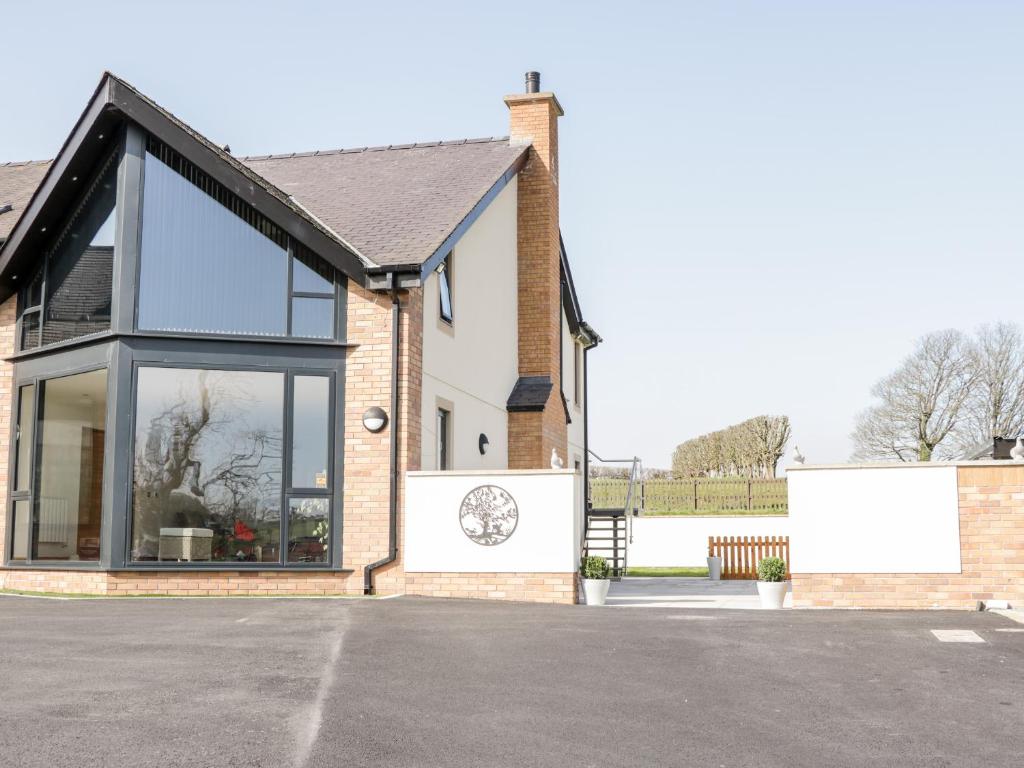 a house with large glass windows and a driveway at The Annexe in Llanfairpwllgwyngyll