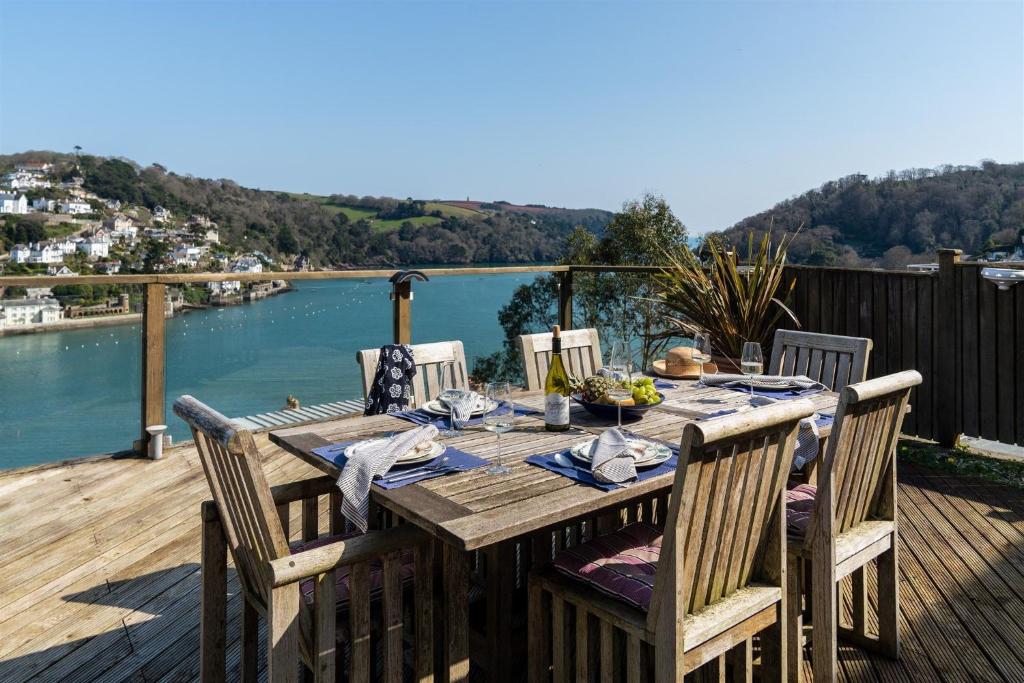 a wooden table on a deck with a view of the water at Uphigh - Elevated Family Home with Stunning River Views in Dartmouth