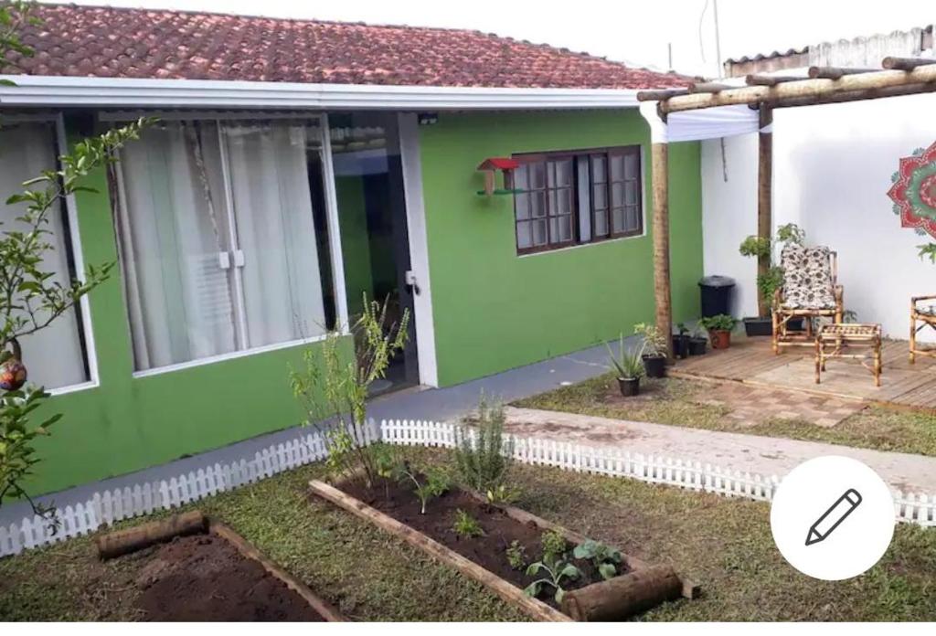 a green house with a garden in front of it at Edícula - Casa de hospedes - em Cananeia SP com ar condicionado in Cananéia