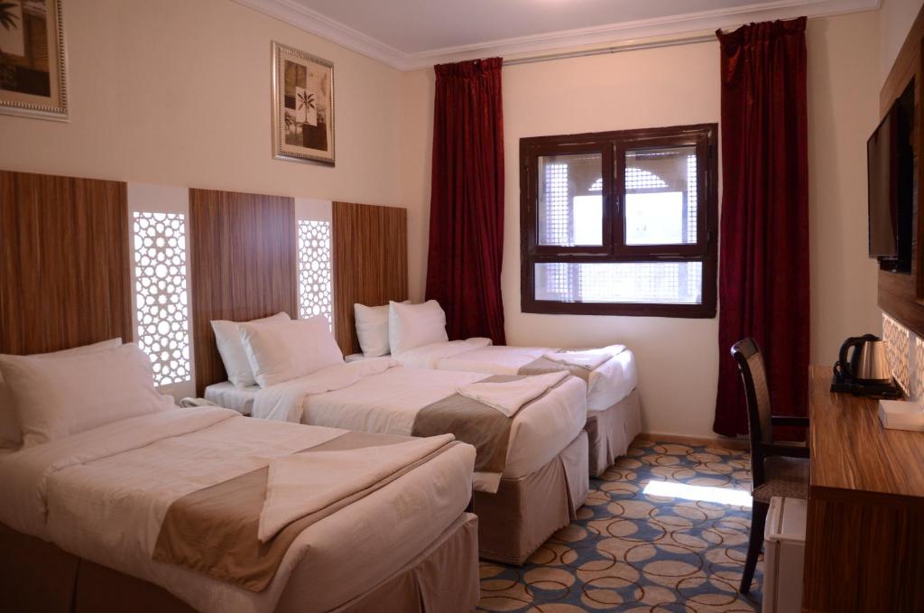 a hotel room with two beds and a window at Artal Al Alami Hotel in Al Madinah