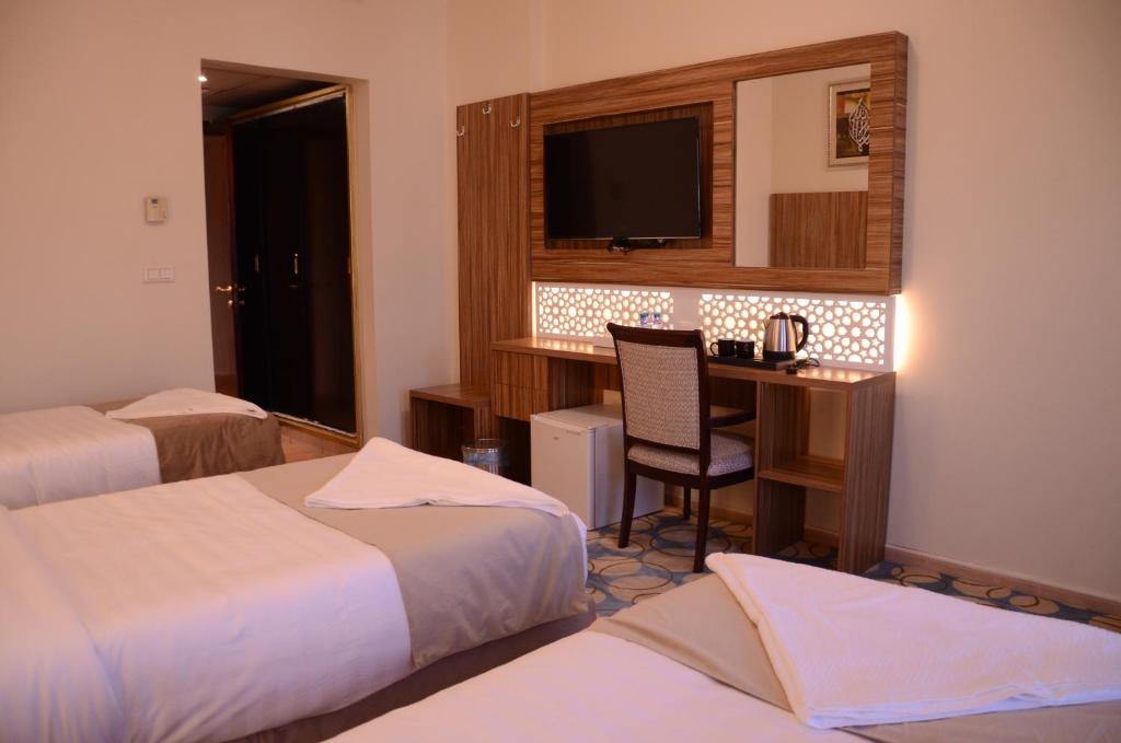 a hotel room with two beds and a desk with a television at Artal International Hotel in Medina