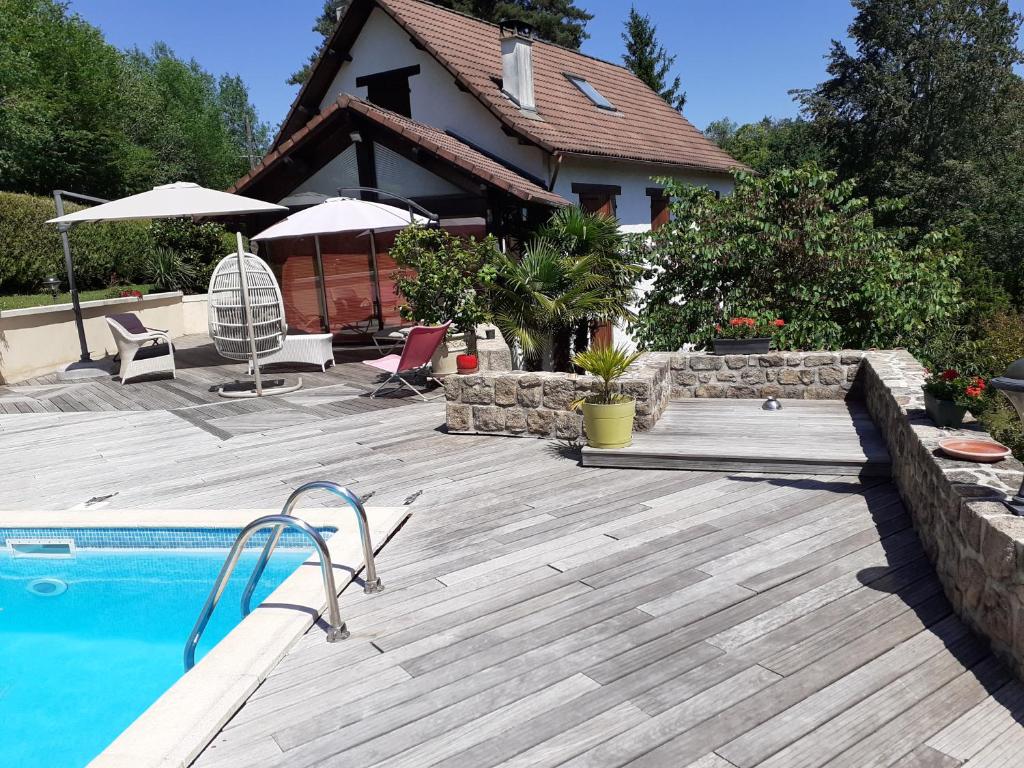 un cortile con piscina e una casa di Chambre d'hôtes un petit coin de paradis en Corrèze a Laguenne