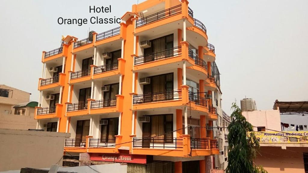 an orange and white building with balconies on it at Hotel Orange Classic in Rishīkesh