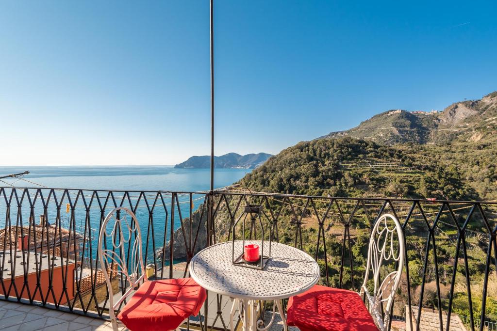 einen Tisch und Stühle auf einem Balkon mit Meerblick in der Unterkunft Rossi Tramonti 1, in Corniglia