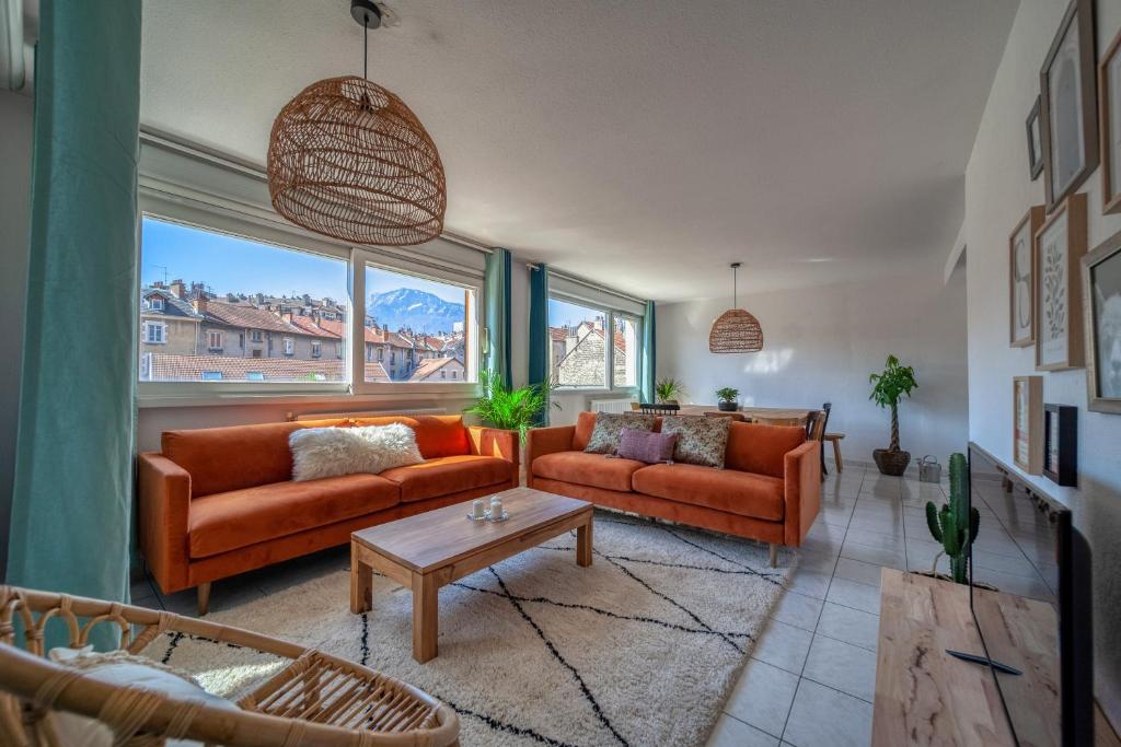 a living room with two orange couches and a table at Le Reverso, T6 en duplex & vue incroyable in Grenoble