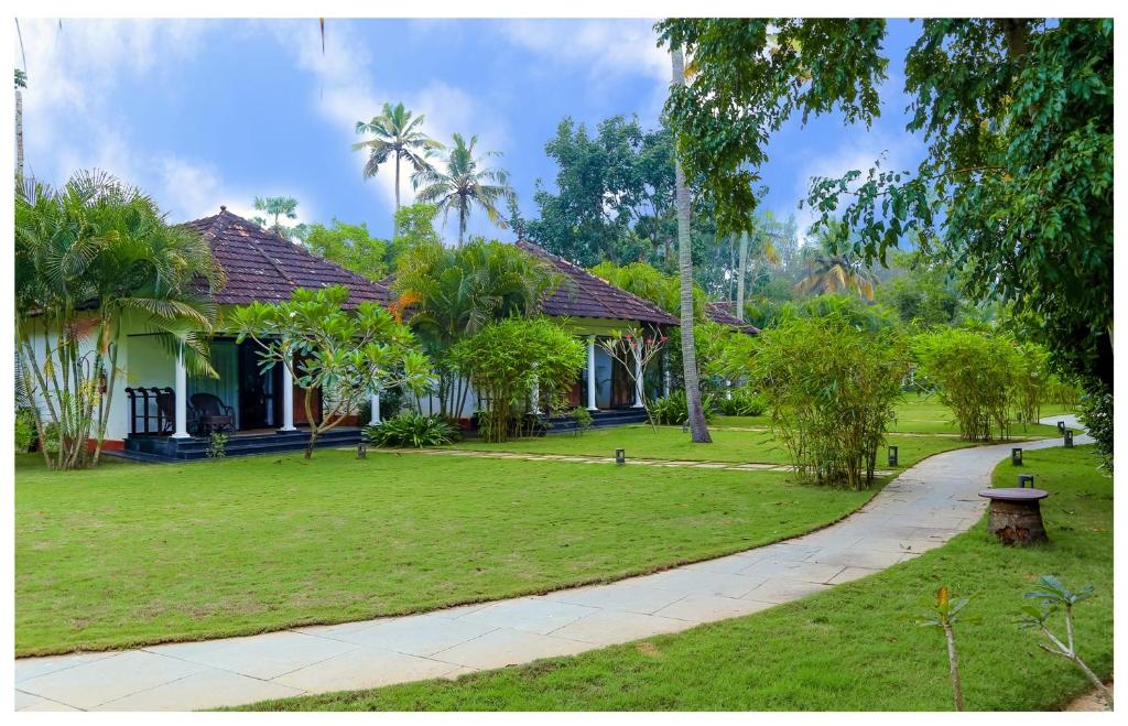 una casa con un patio verde con una acera en Seclude Kerala, Marari Sands, en Mararikulam