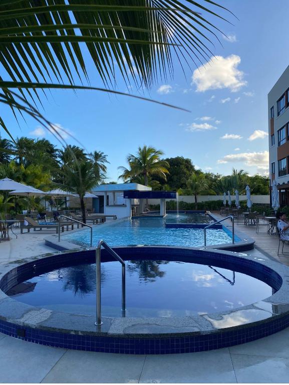 a large swimming pool in a resort with trees at Condomínio Paraiso dos Coqueiros in Camacari
