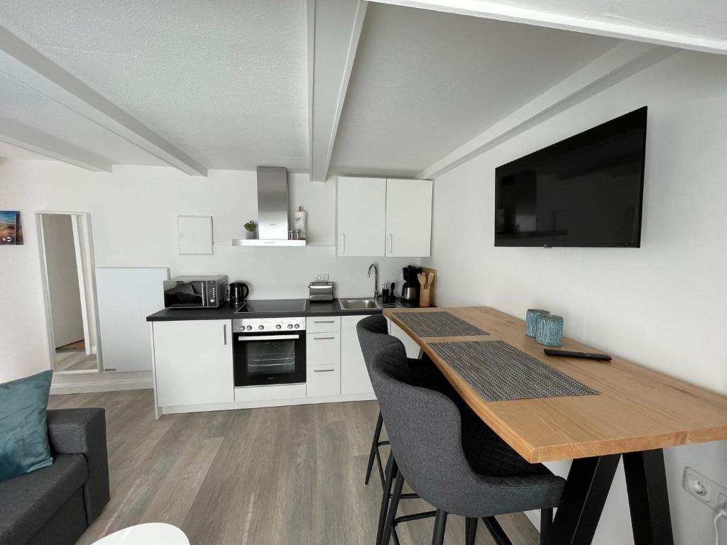 a kitchen with a table and chairs and a kitchen with a tv at Juna in Laboe