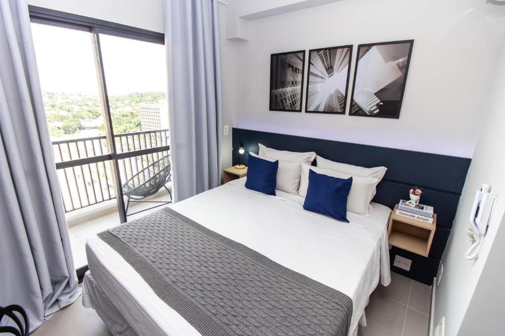 um quarto com uma cama com almofadas azuis e uma varanda em 360 Brooklin em São Paulo