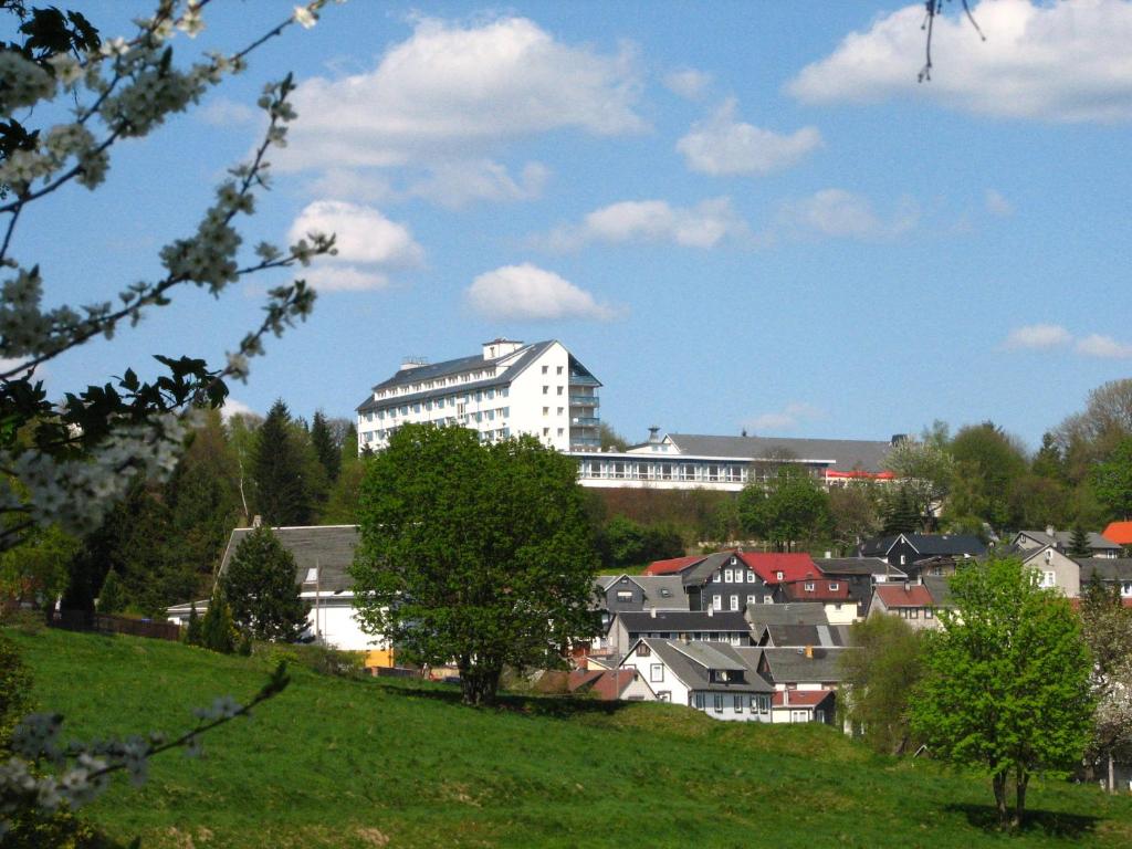 Eine Stadt mit einem großen weißen Gebäude auf einem Hügel in der Unterkunft Werrapark Resort Hotel Frankenblick in Masserberg