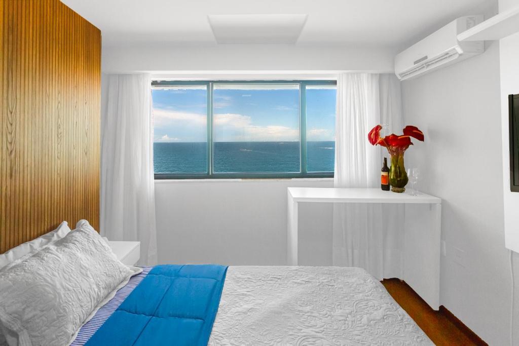 a bedroom with a bed and a large window at Suite Praia da Costa Confort in Vila Velha