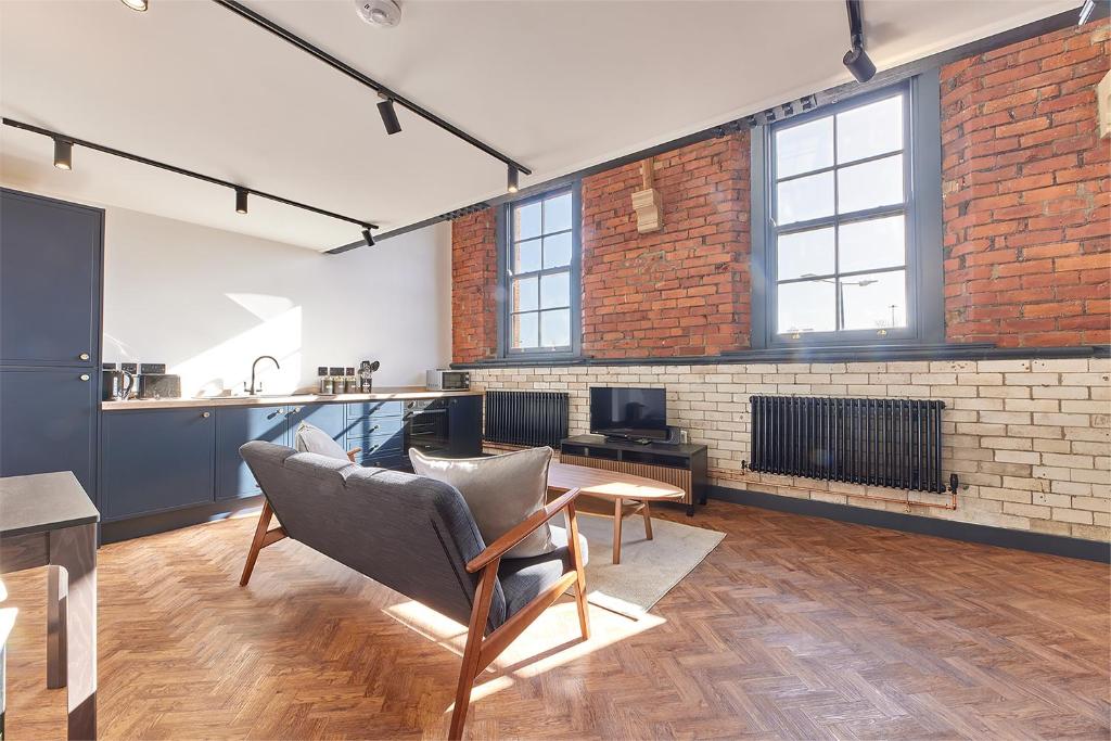 a loft with a brick wall and a table and chairs at No 6 at Simpson Street Apartments Sunderland in Sunderland