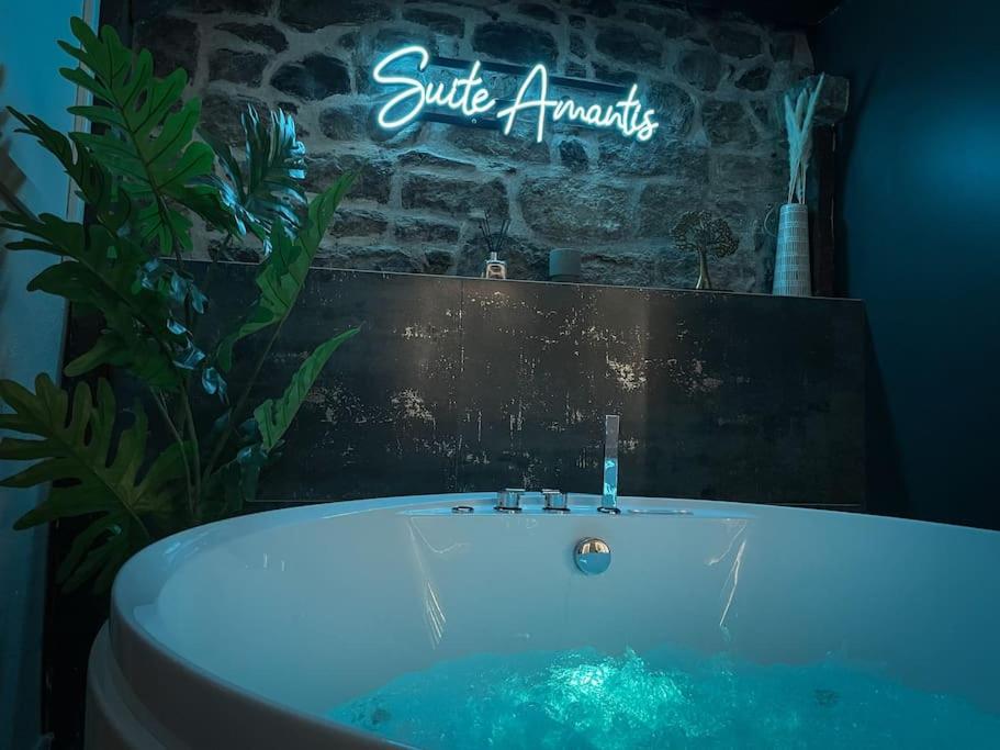 uma banheira numa casa de banho com um sinal que lê superficialysis em SUITE AMANTIS évadez vous dans l'univers MYKONOS em Saint-Chamond