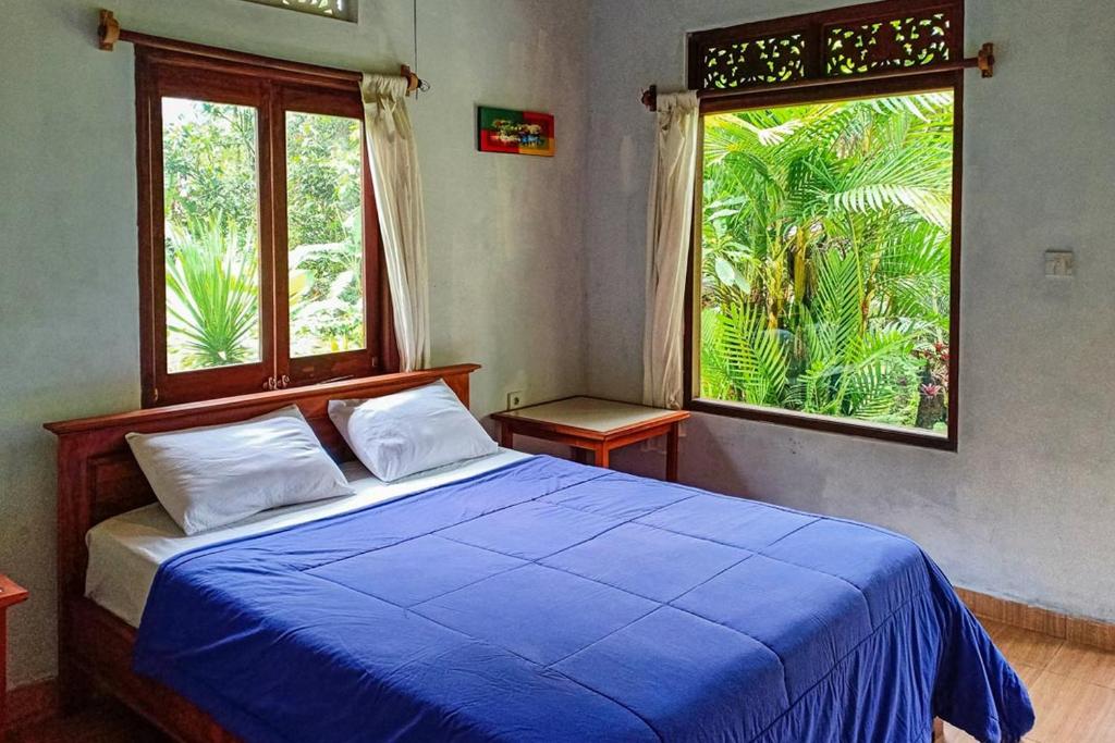 a bedroom with a blue bed and a large window at Dina Home Stay at Desa Wisata Wongayagede in Jatiluwih