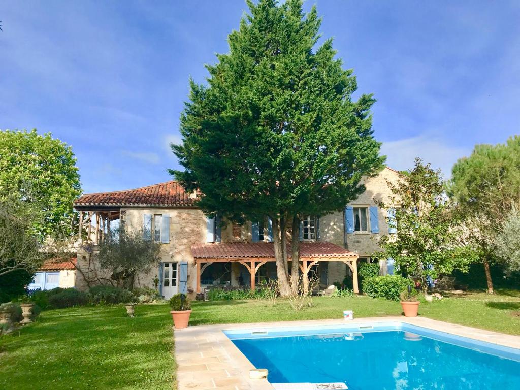 a house with a swimming pool in front of a tree at Le Relais des Anges in Mercuès