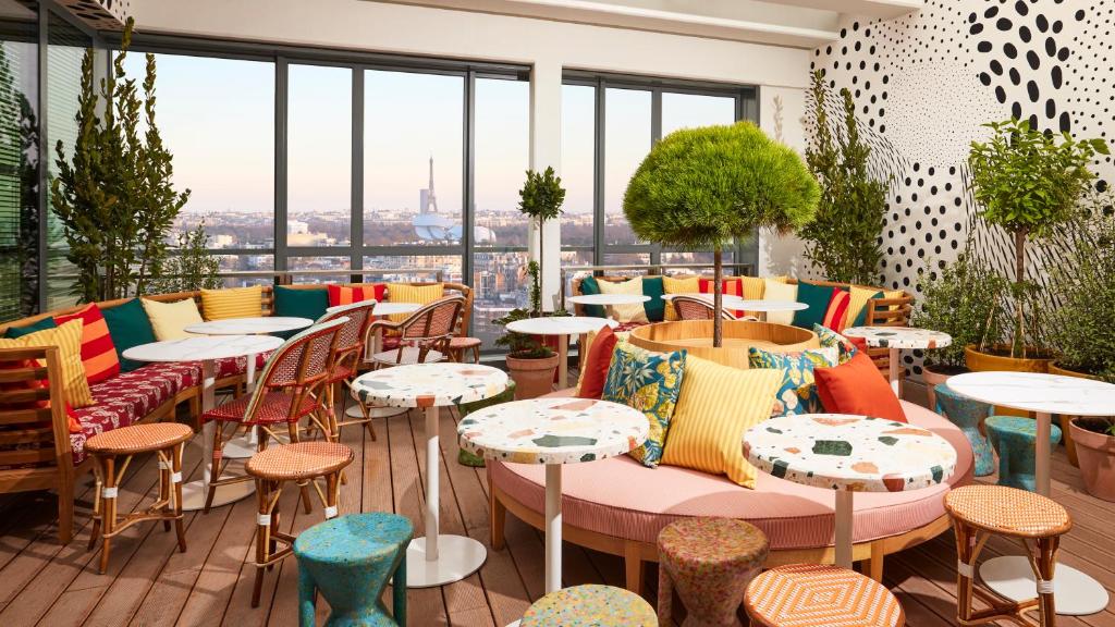 un restaurant avec des chaises, des tables et des fenêtres colorées dans l'établissement Mama Shelter Paris La Défense, à Puteaux