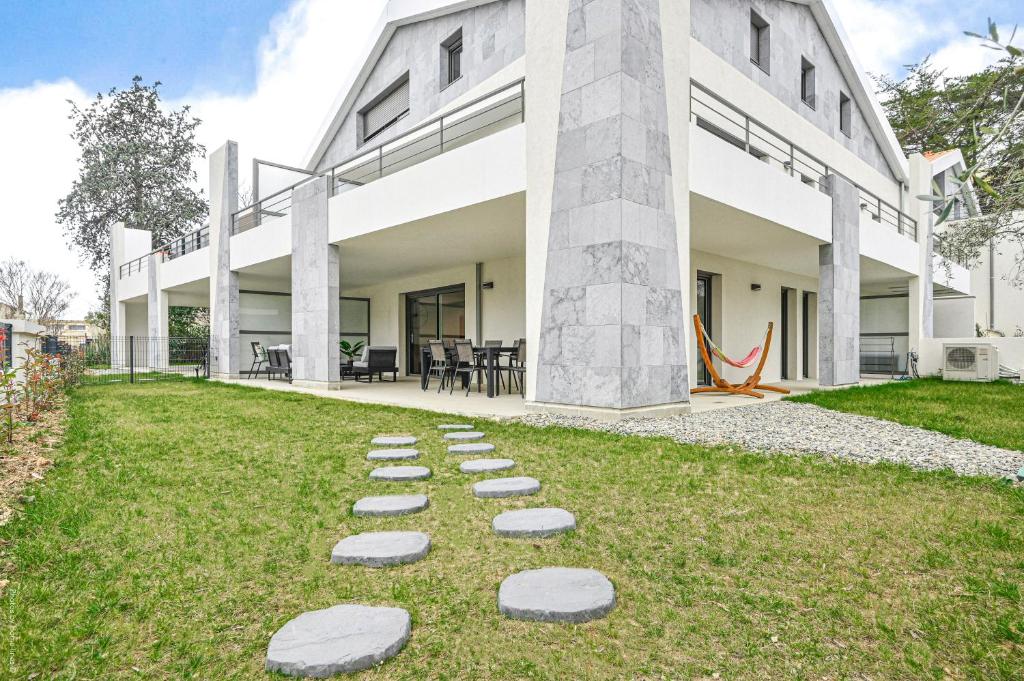 Une rangée de pas sur l'herbe devant un bâtiment dans l'établissement T4 NEUF - JARDIN-TERRASSE ET PISCINE – ACCÈS DIRECT PLAGES ET CENTRE VILLAGE – App C 12, à Saint-Cyr-sur-Mer