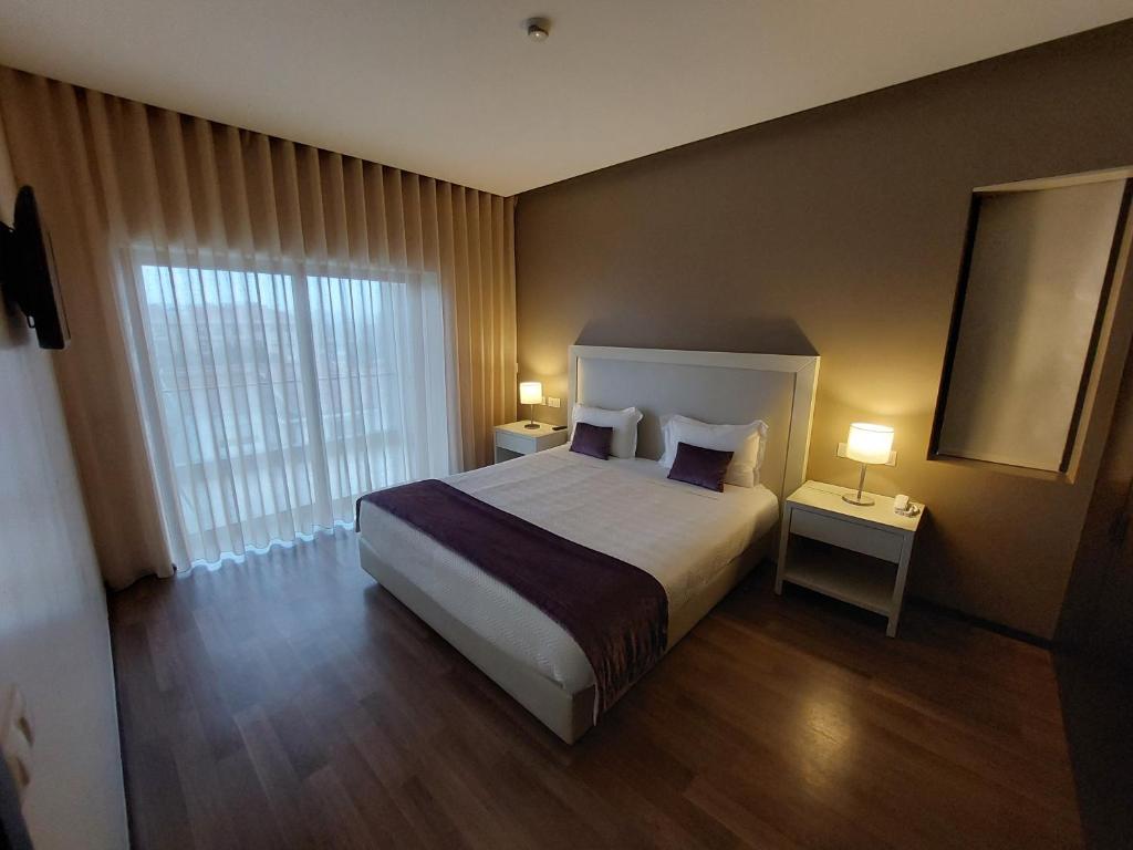 a hotel room with a bed and a window at Hotel Monte Lírio in Espinho